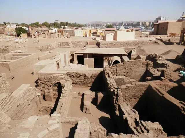 Ancient stone ruins and excavated structures in a desert landscape under a clear sky.