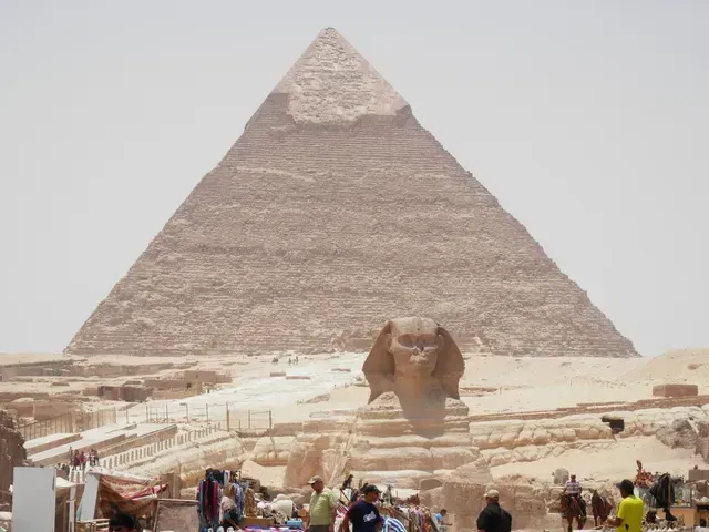 The Great Pyramid of Giza with the Sphinx in the foreground under a hazy sky.