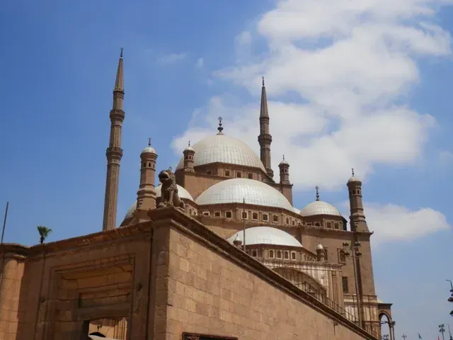 Historic mosque with tall minarets and domes against a blue sky