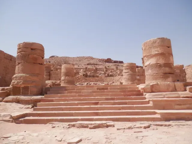 Ancient stone steps and ruins in a desert landscape under a clear blue sky