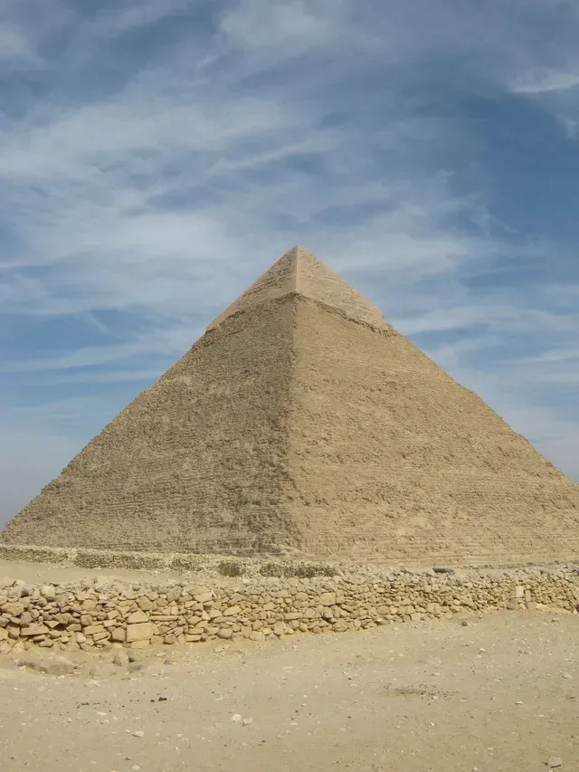 Pyramid in a desert under a partly cloudy sky