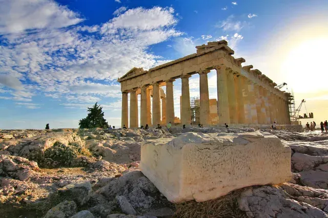 Ancient stone temple ruins on a rocky hill at sunset under a blue sky