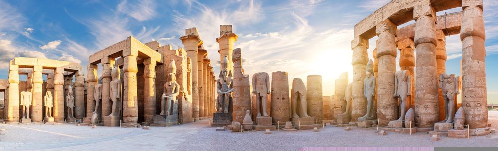Ancient stone temple ruins at sunrise, with columns and warm golden light against a snowy ground.