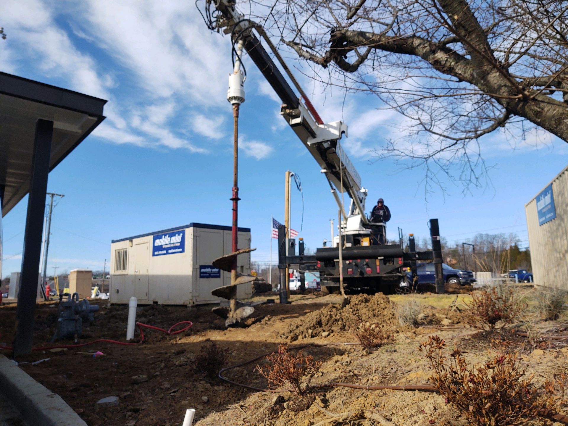 A crane is lifting a pole into the ground