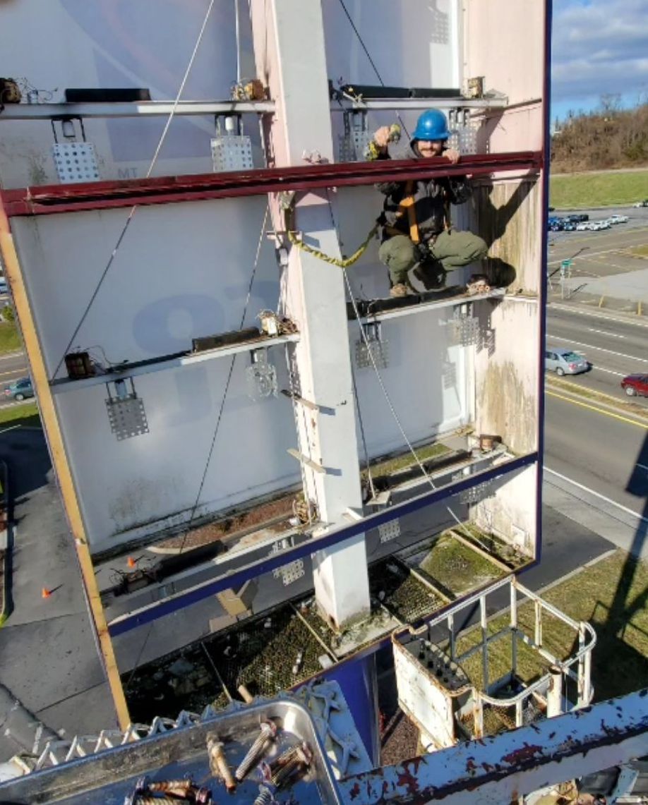 A large sign for a restaurant is being installed by a crane.