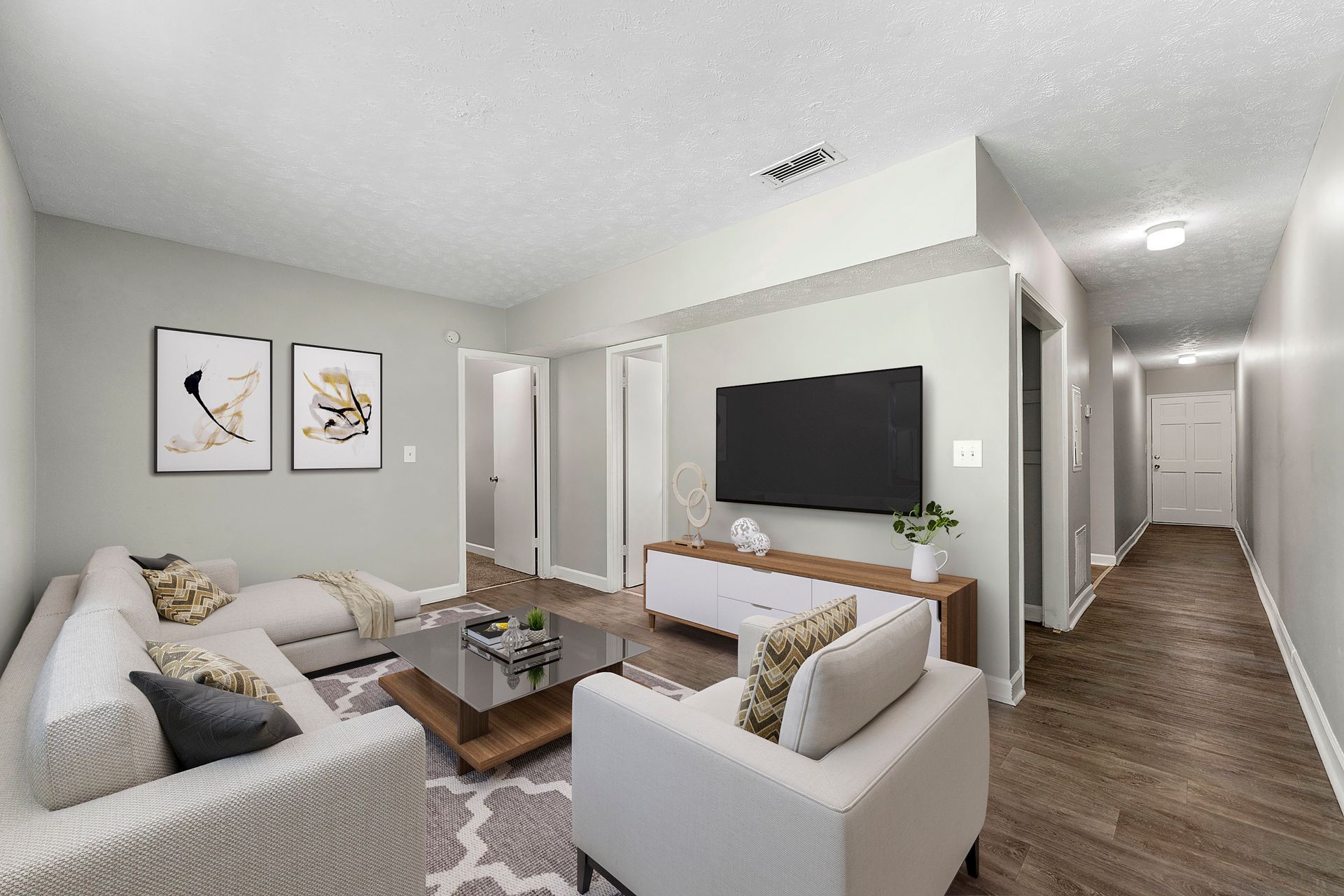 Bright modern living room with gray sofas, wall-mounted TV, coffee table, and hallway view