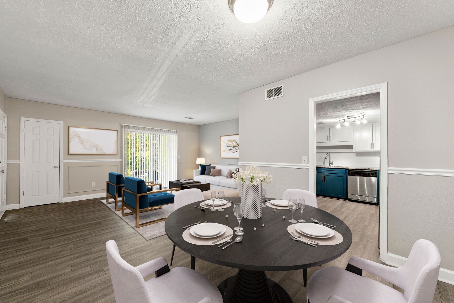 Open dining area with dark round table, white chairs, blue sofa, and sliding glass doors to a patio.