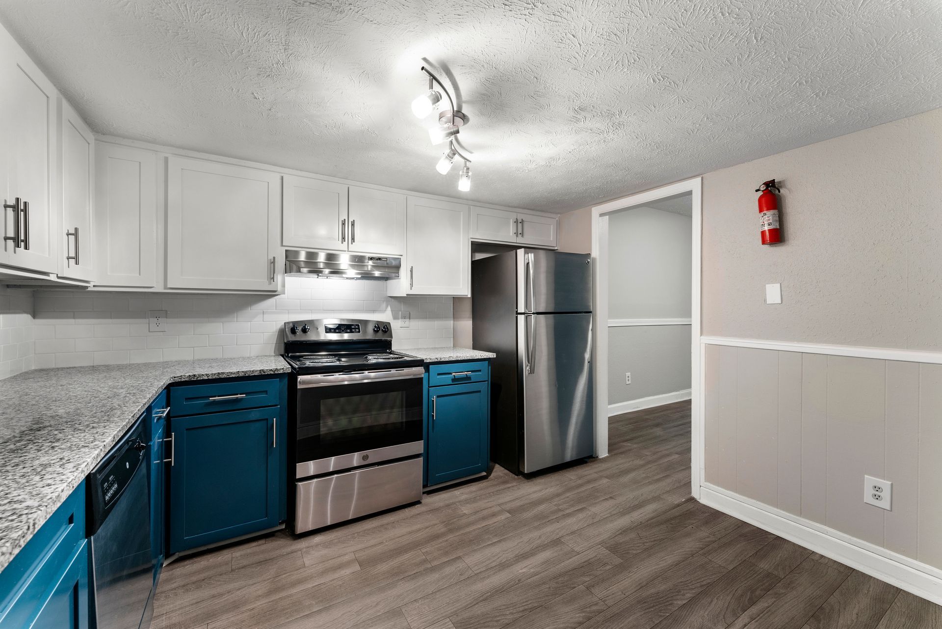 Modern kitchen with stainless steel appliances, blue cabinets, gray flooring, and white walls