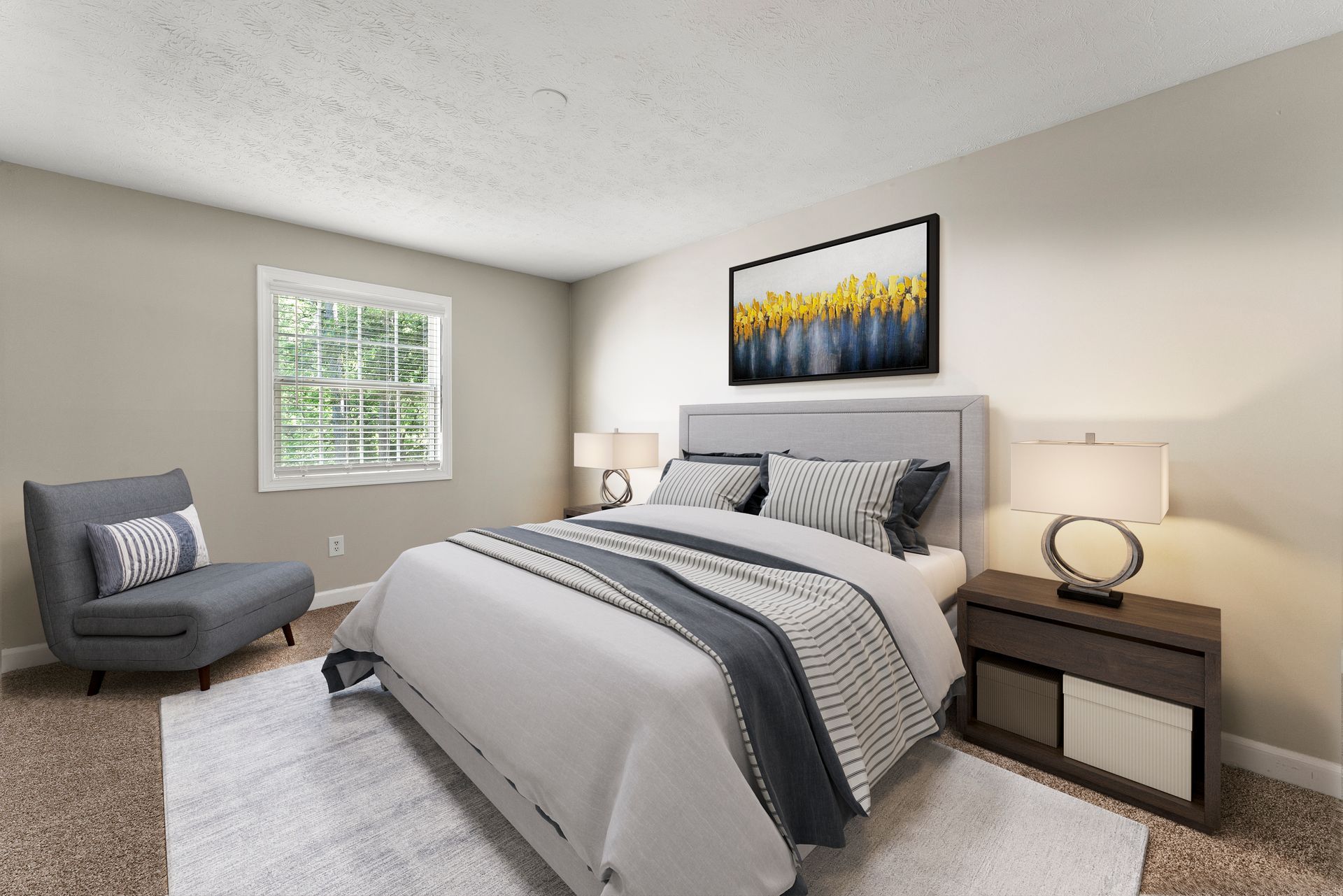Bright bedroom with a gray bed, matching chair, nightstands, lamp, window, and abstract wall art.