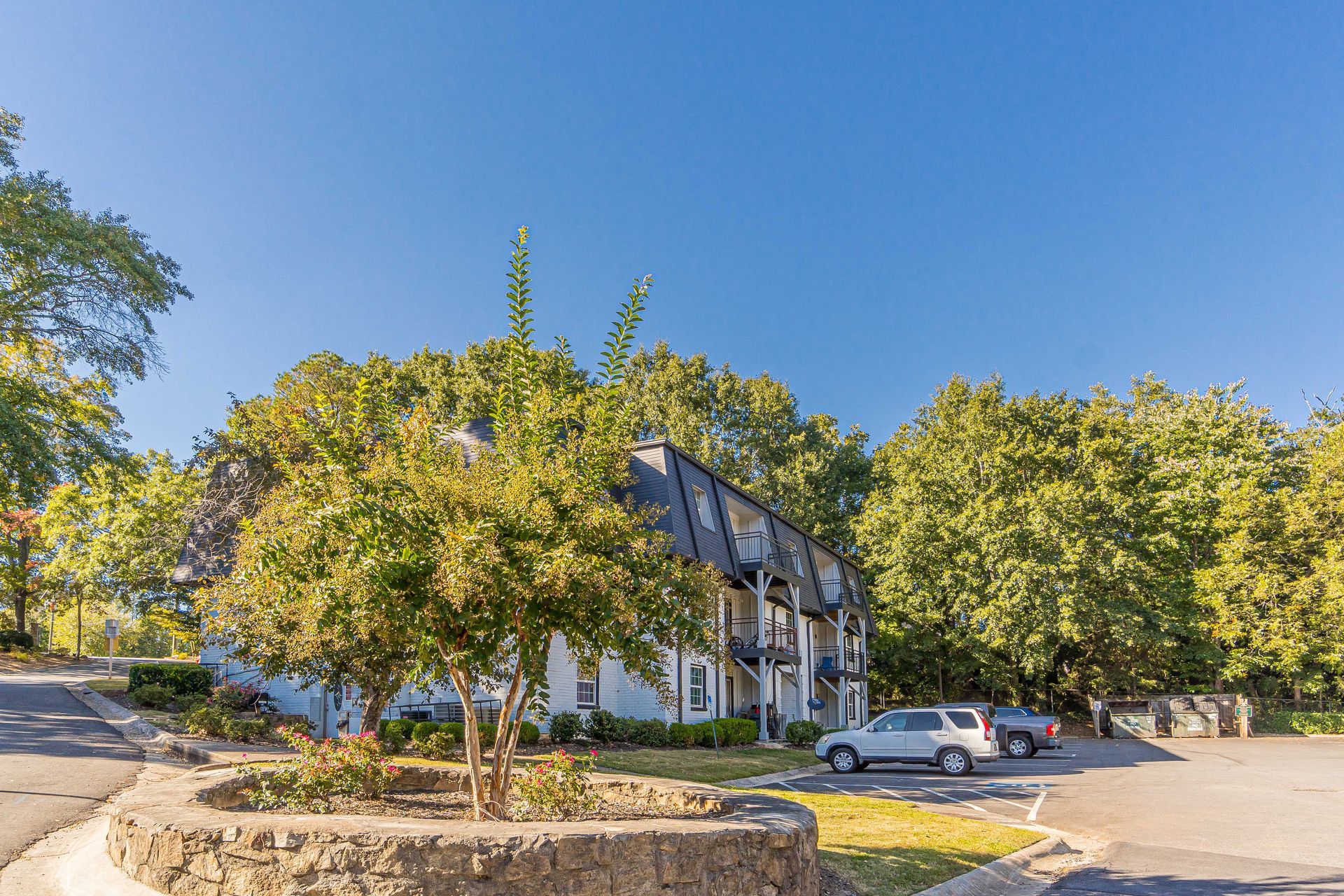 Apartment building with trees and parked cars on a sunny day