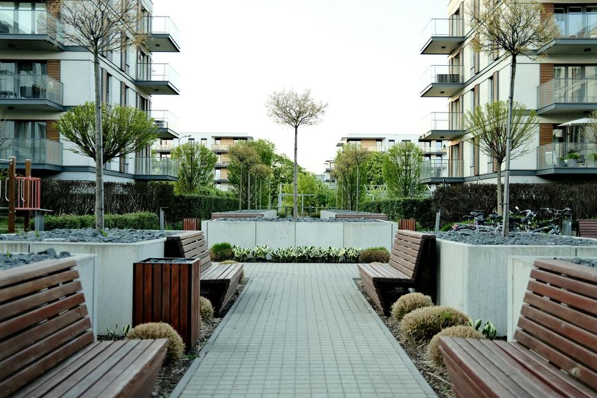 Modern apartment courtyard with benches, planters, and a paved walkway between buildings