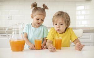 Duas Crianças bebendo suco de laranja