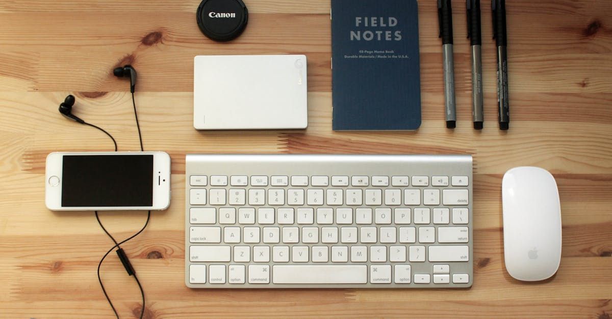 A wooden desk with a keyboard a phone a notebook and a mouse