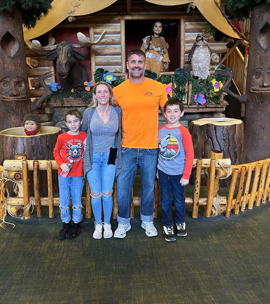 Family of four posing in front of a colorful tiki-style display indoors