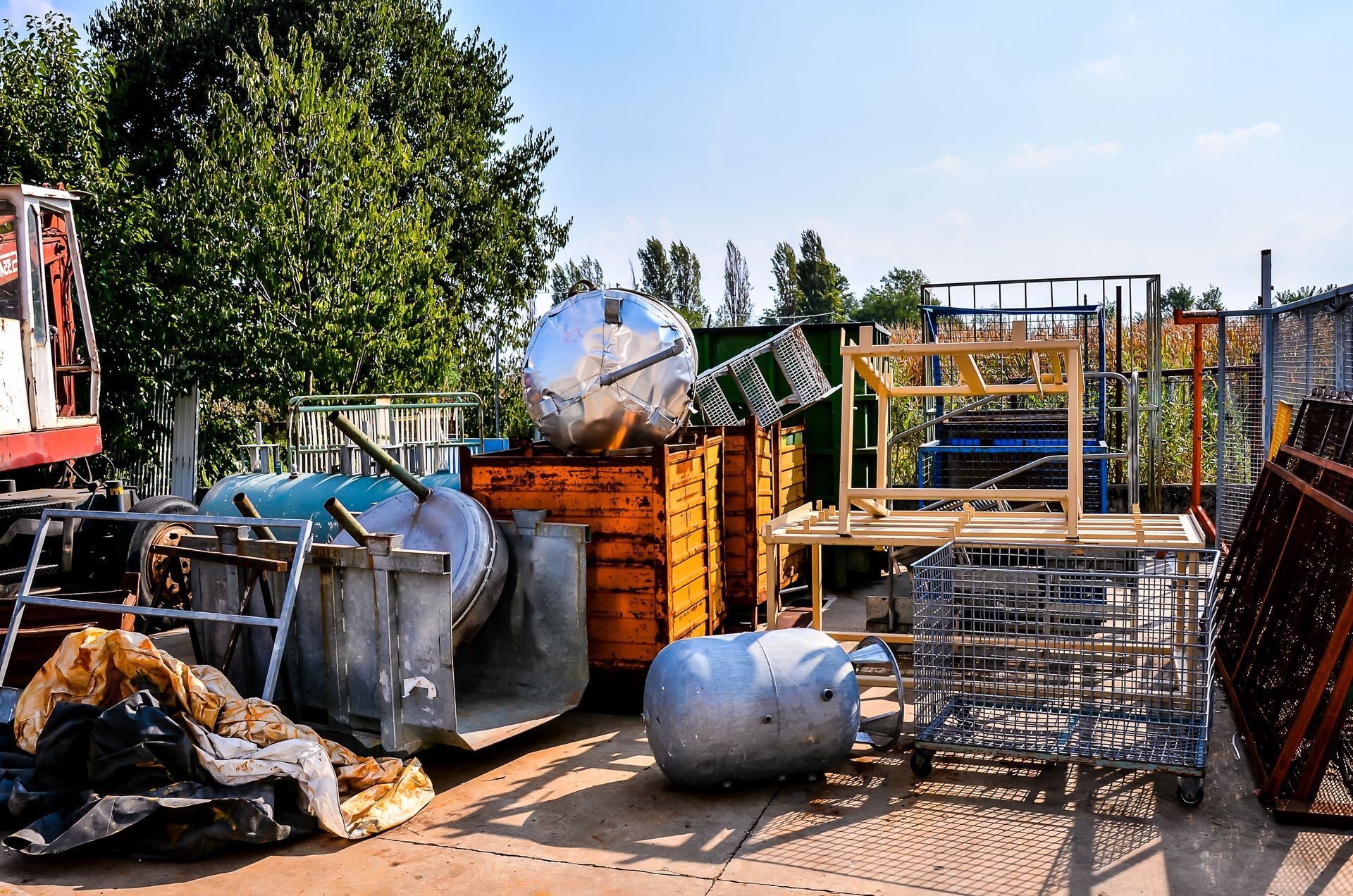 Piles of metal debris and scrap bins in an outdoor industrial yard under bright sun