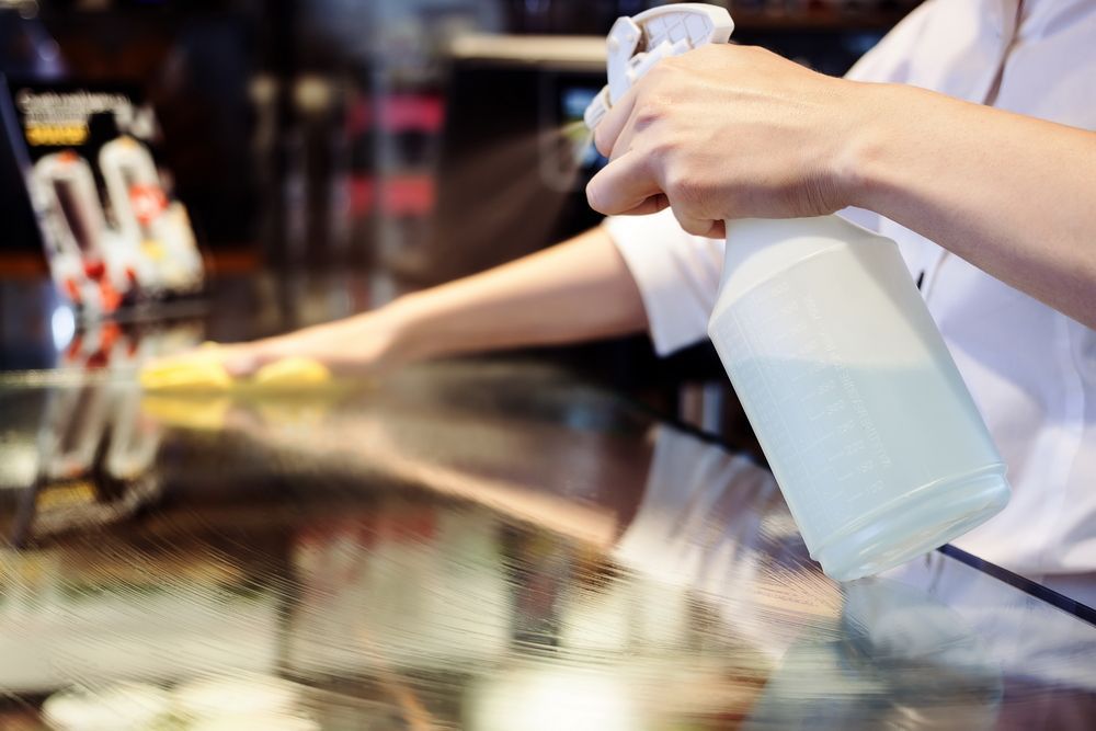 A person is cleaning a table with a spray bottle.