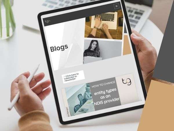 Hands holding a tablet showing a blog website with photos and text blocks