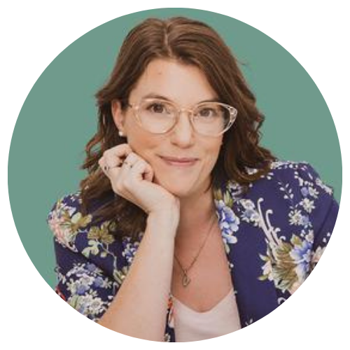 Portrait of a woman with glasses resting her chin on her hand against a teal background