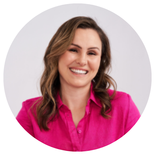 Smiling woman in a bright pink blouse against a light gray background