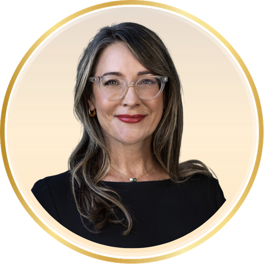 Portrait of a smiling woman with glasses and dark hair on a light beige background, framed by a gold circle