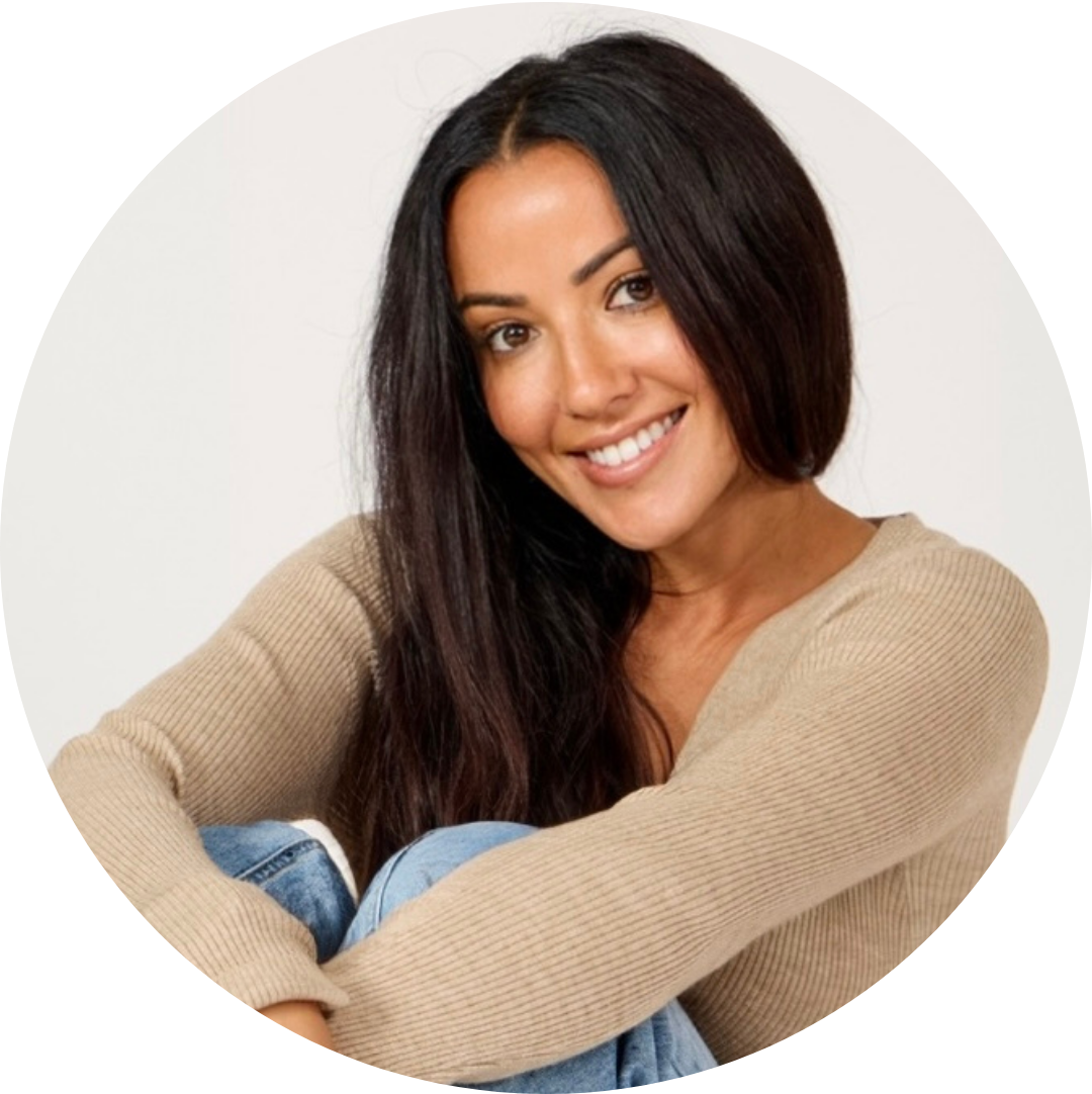 Smiling woman with long dark hair in a beige sweater, seated against a white background