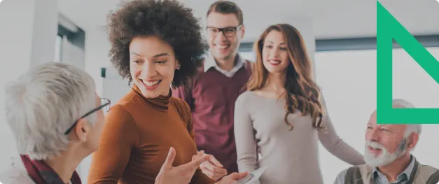 Four people in a bright office smiling and talking in a casual group discussion