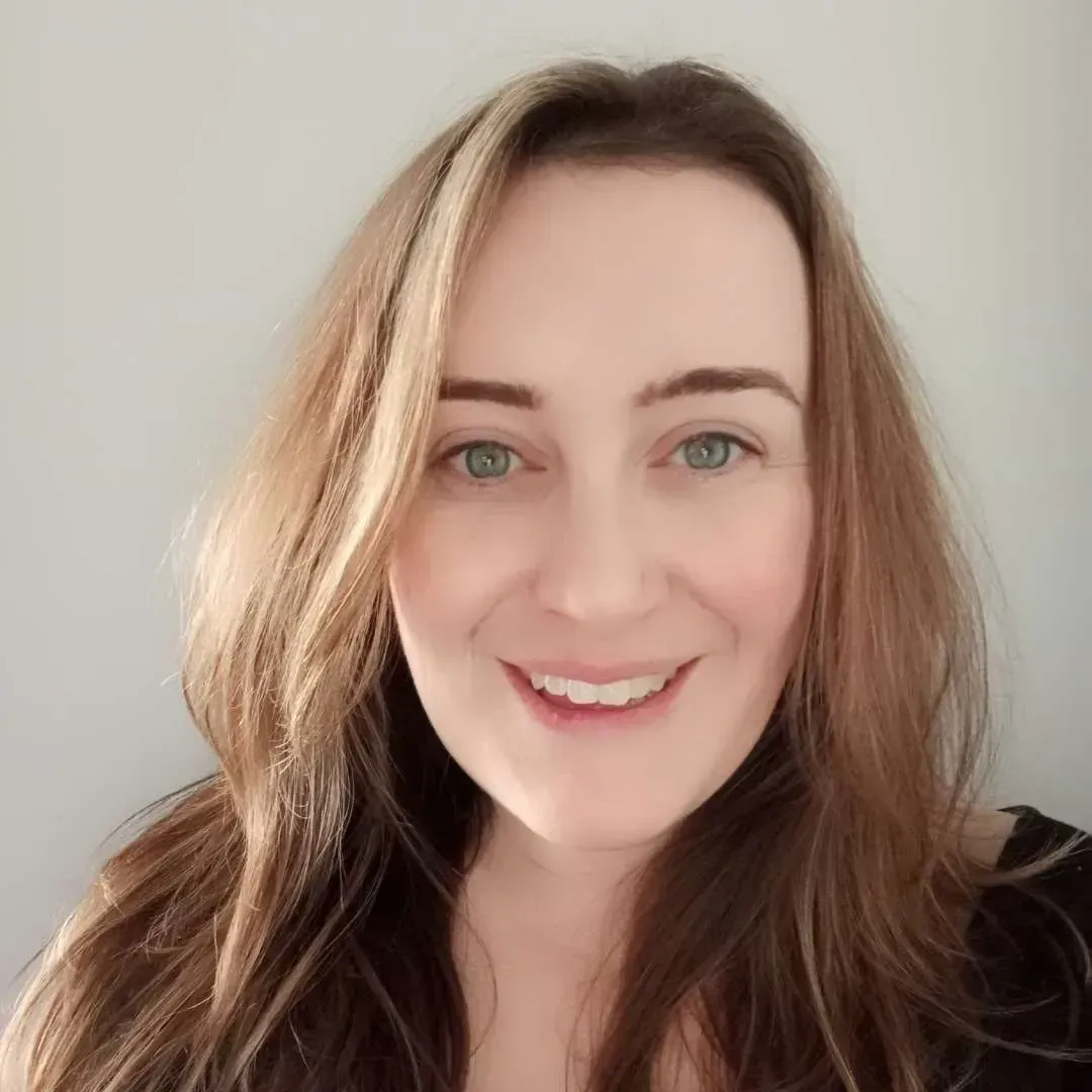 Smiling woman with long light brown hair against a plain light background