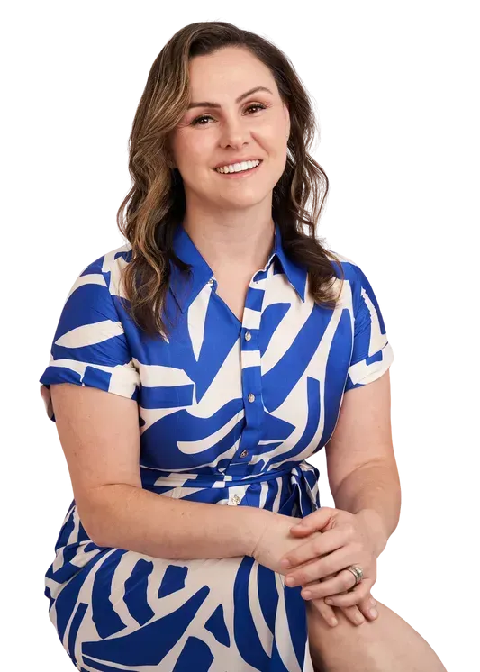 Woman seated in a blue-and-white patterned dress, smiling against a white background