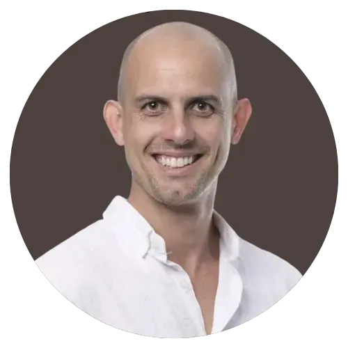 Smiling bald man in a white shirt against a dark brown background