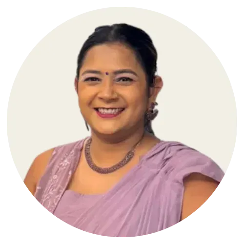 Smiling person in a lavender saree against a light background