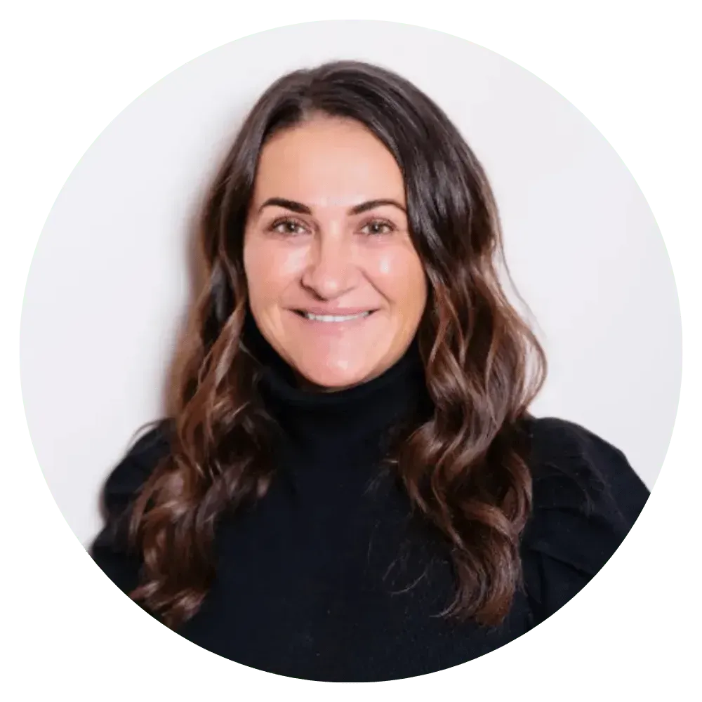 Smiling woman with long brown hair wearing a black turtleneck against a white background