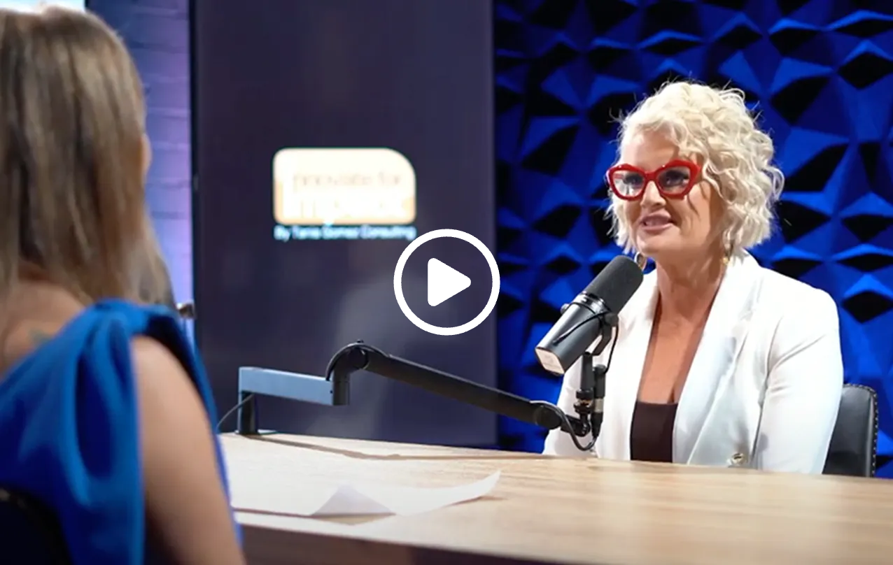 Podcast host in blue interviews a guest at a microphone in a studio setting