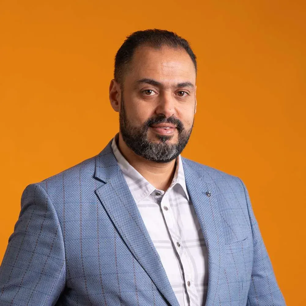 Studio portrait of a man in a blue blazer against an orange background