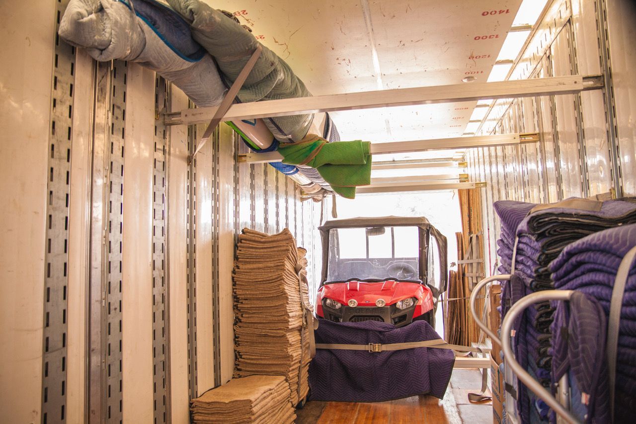 The inside of a moving truck filled with blankets and a golf cart.