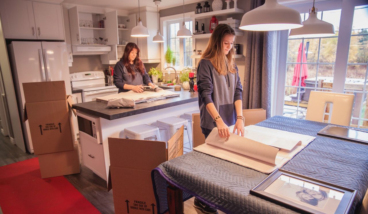 A woman is sitting at a table in a kitchen holding a piece of paper.