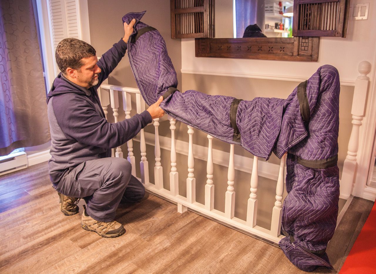 Un homme est agenouillé à côté d'une balustrade, enveloppé dans une couverture violette.