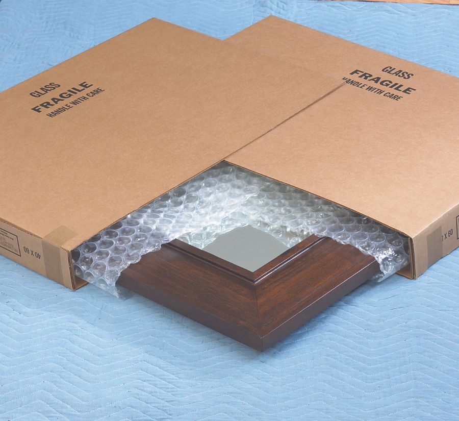 Miroir dans un cadre marron, emballé dans du papier bulle, dans une boîte en carton pour l'expédition.