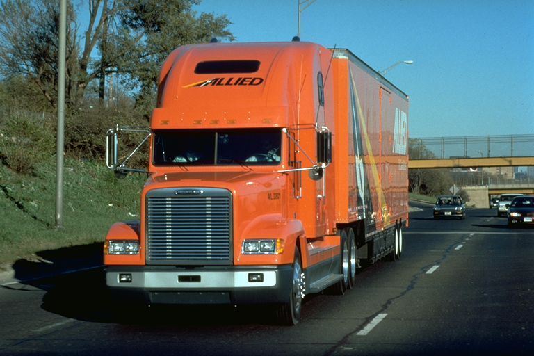 Camion de déménagement Orange Allied sur une autoroute, ciel lumineux, autres véhicules en arrière-plan.
