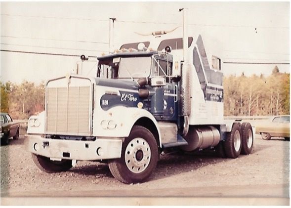 Camion semi-remorque Kenworth vintage blanc et bleu garé à l'extérieur.