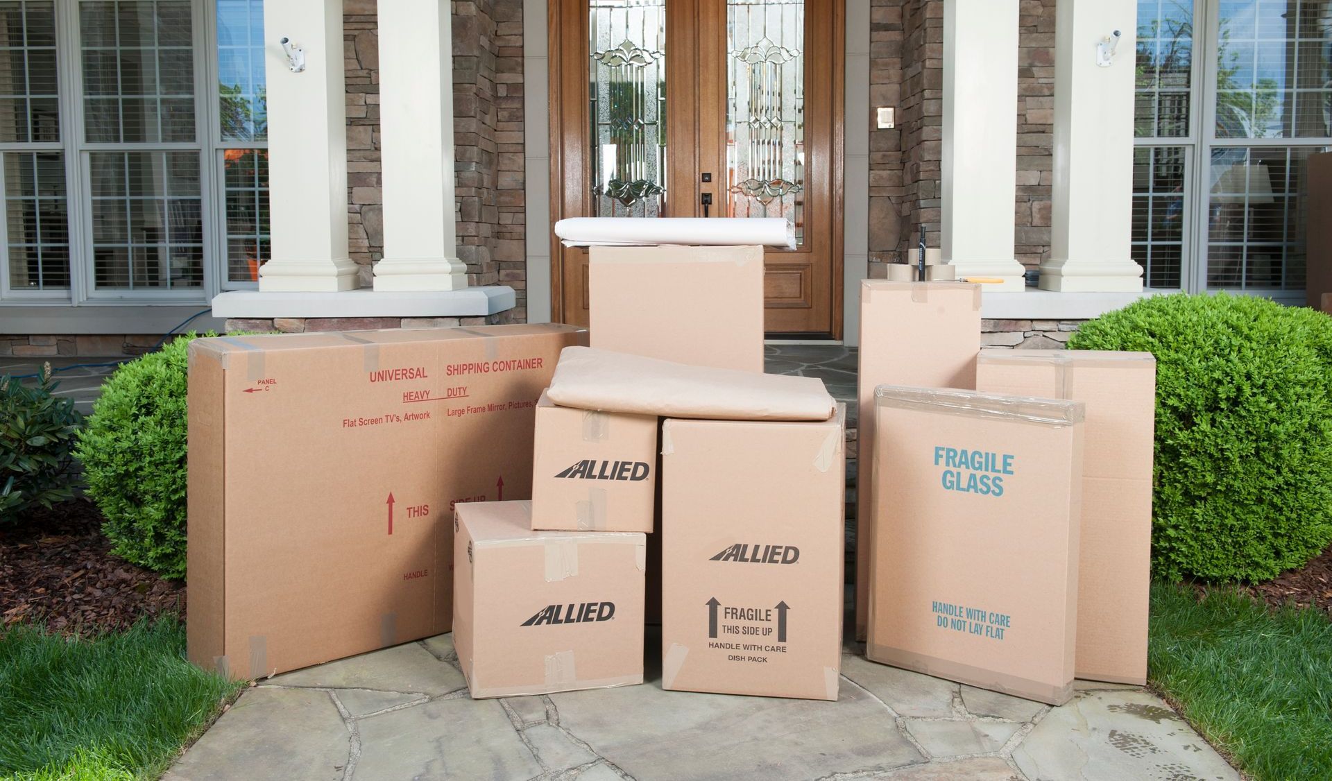 Des cartons de déménagement empilés sur le perron d'une maison.