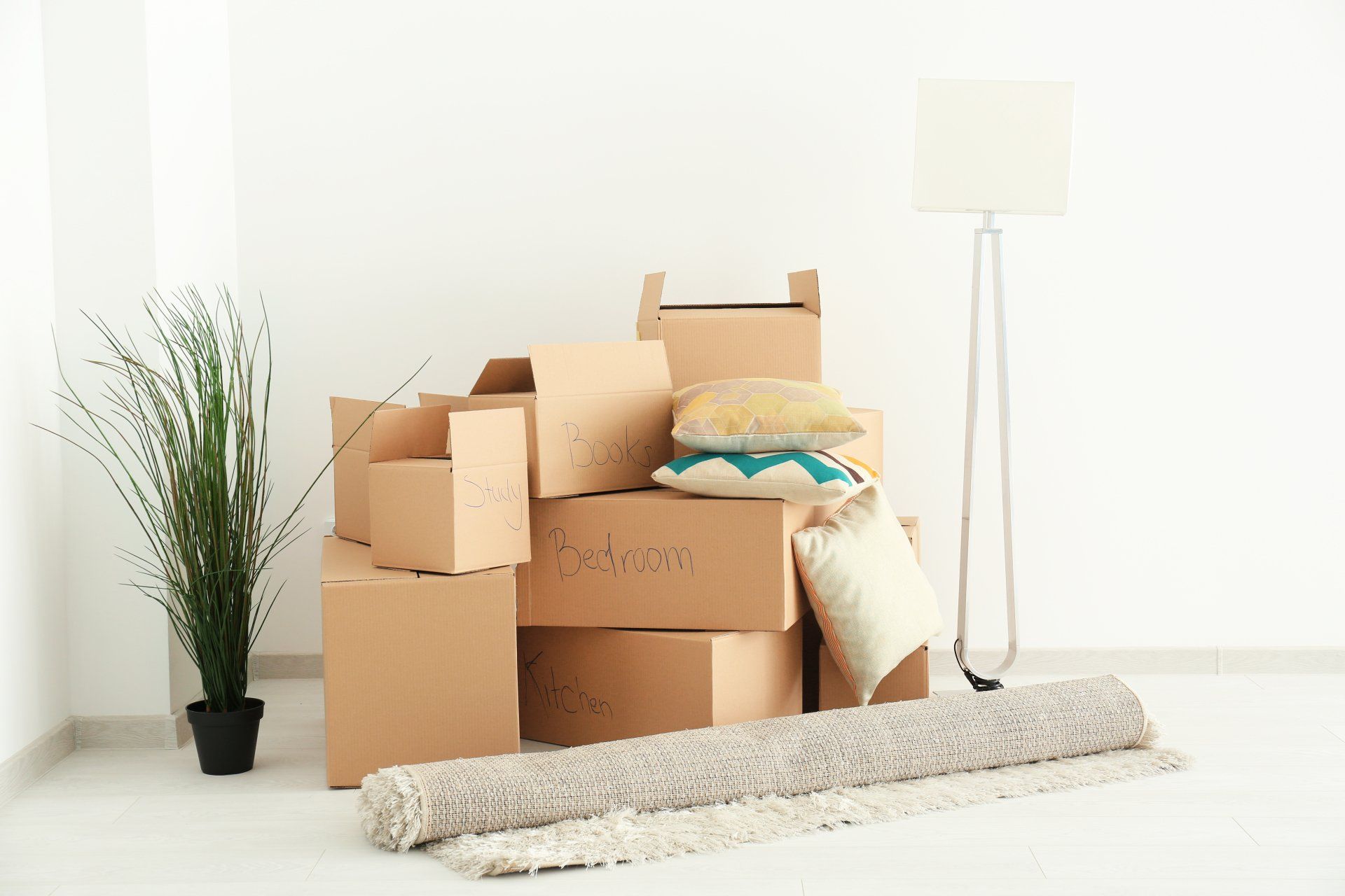 A living room filled with boxes , pillows , a rug and a lamp.