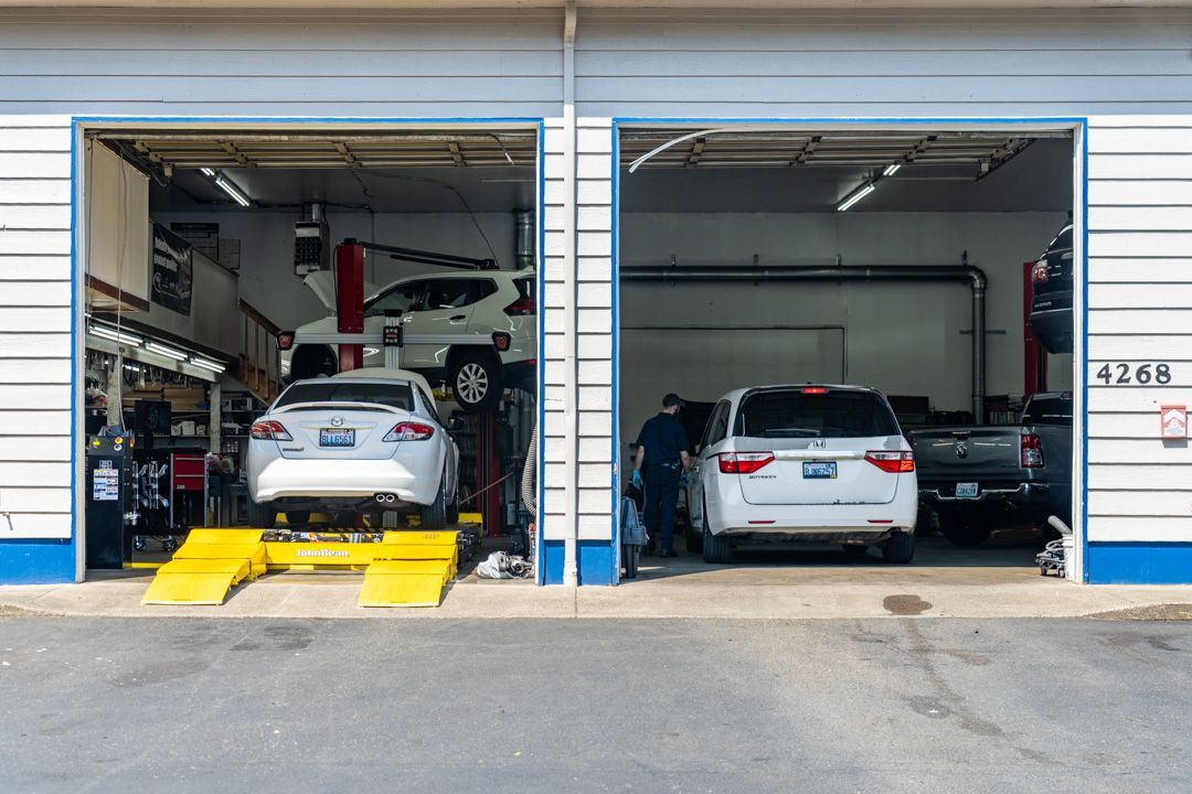 Two cars in a garage bay, one on a lift and one parked inside the workshop.