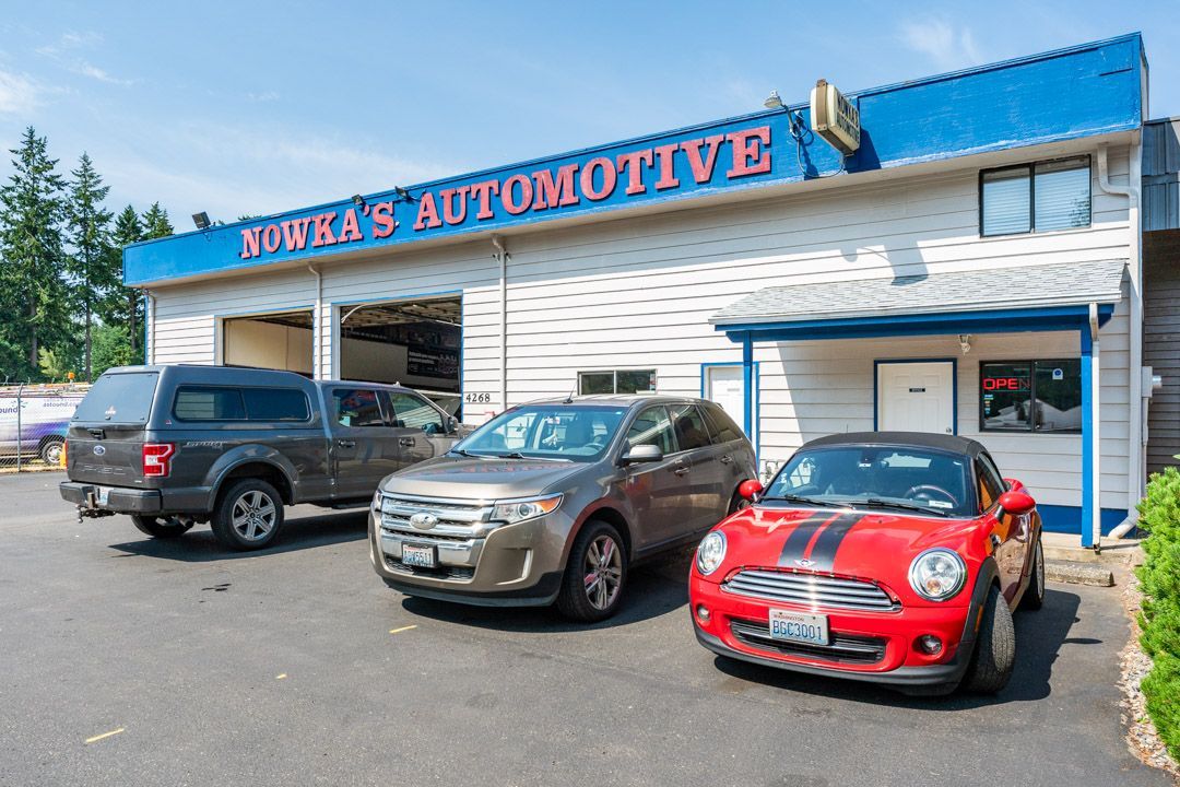Kunk’s Automotive storefront with three parked cars outside, including a red sports car in front.
