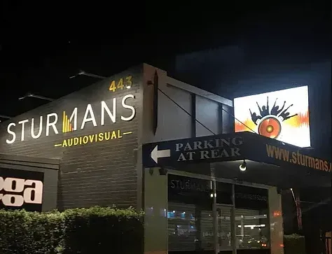 A building with a sign that says `` parking at rear '' is lit up at night.