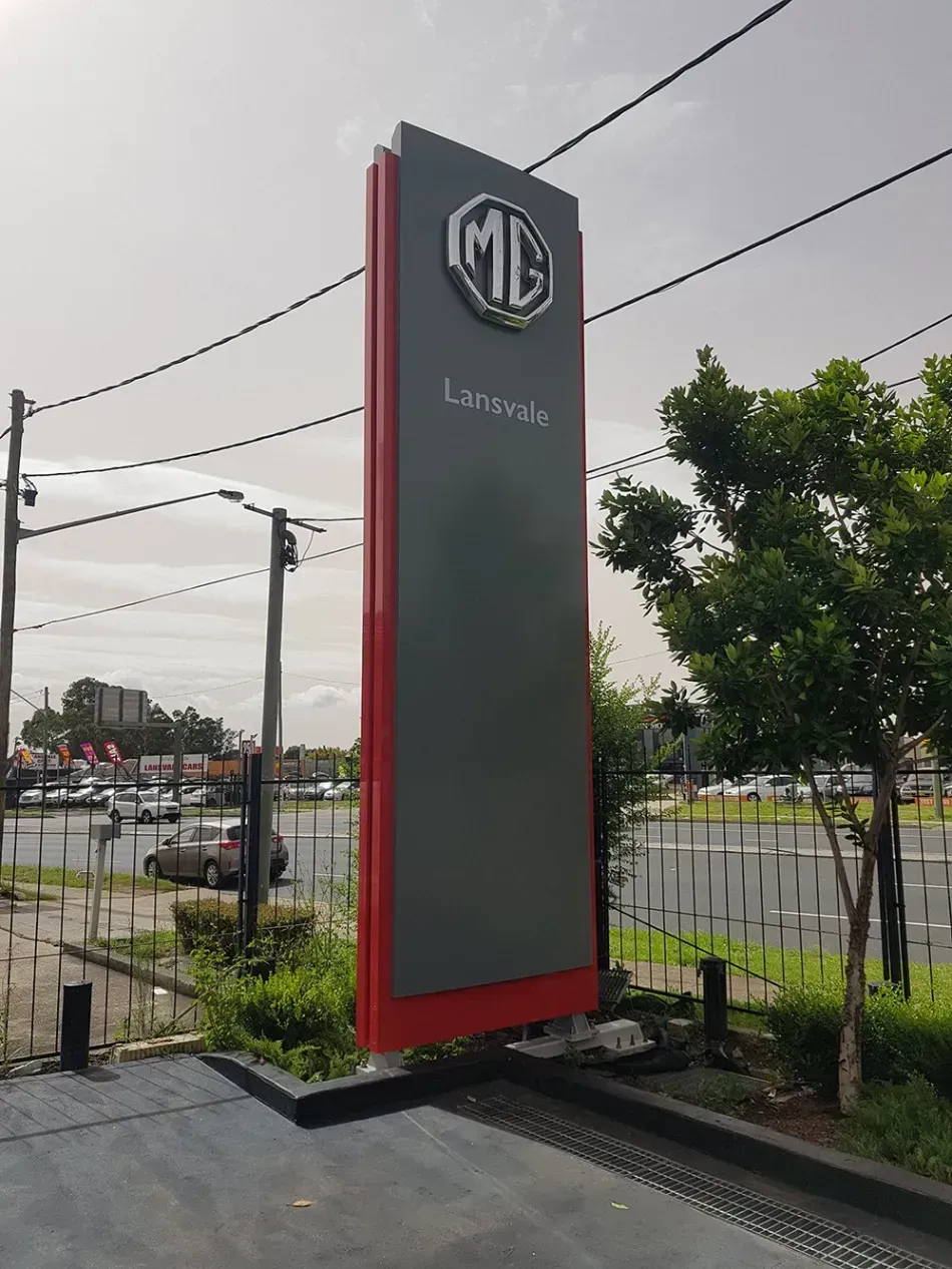 A large sign for a car dealership is sitting in the middle of a parking lot.