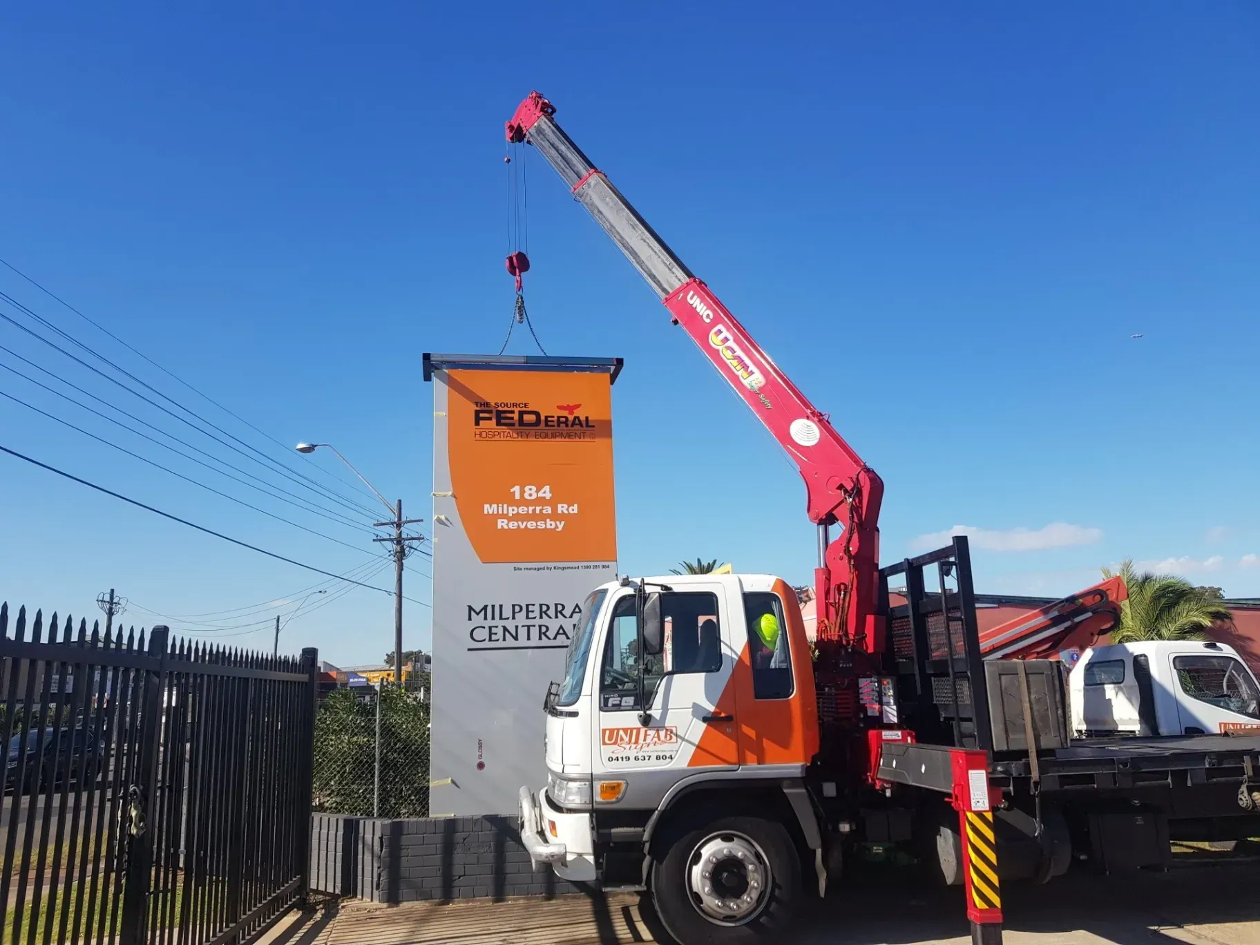 A truck with a crane attached to it is lifting a sign.