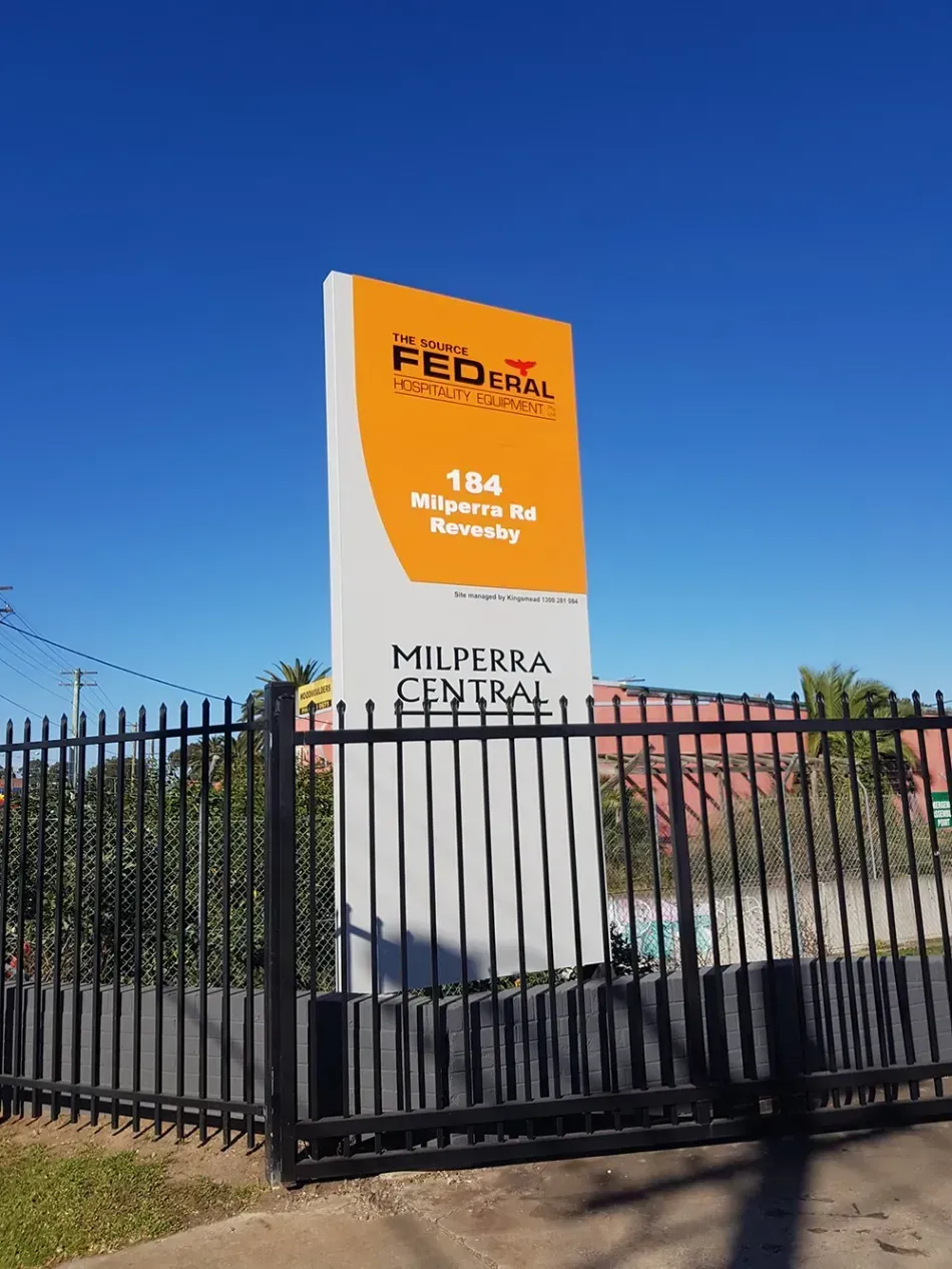 A large sign is sitting in front of a fence.