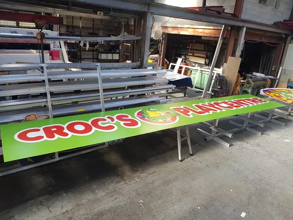 A green sign that says croc 's burgers on it