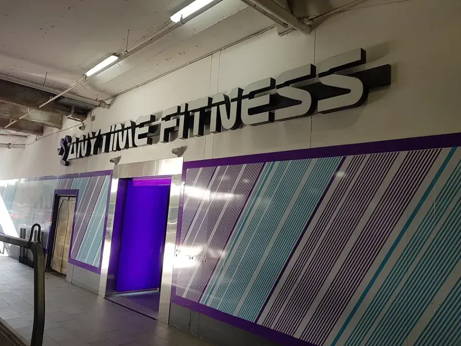 A gym with purple and blue stripes and the word fitness on the wall