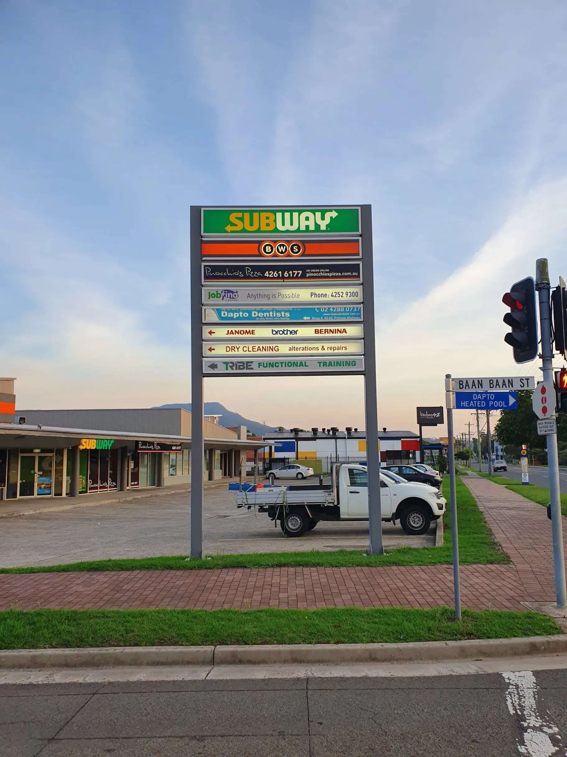 A white truck is parked in front of a subway sign